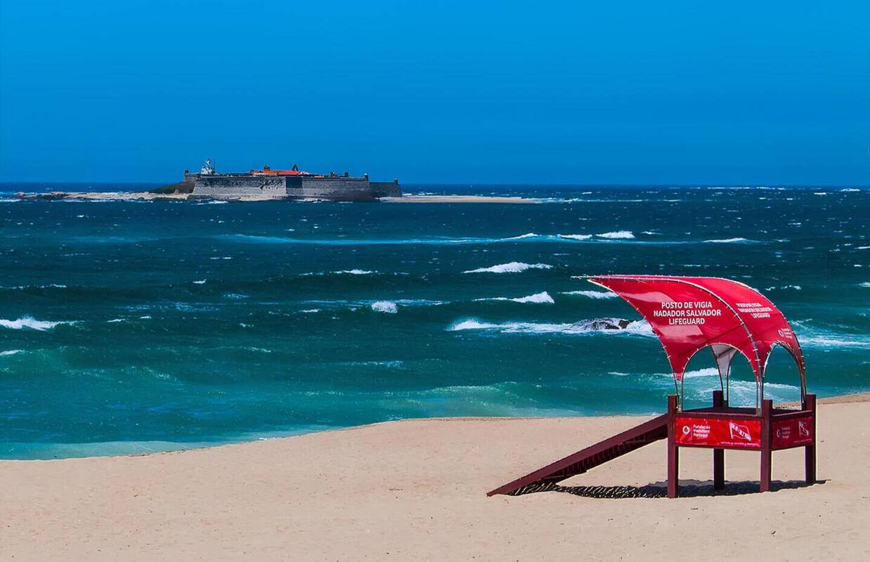 Costa da praia de Moledo, em Caminha, com um posto de salvamento e um navio no fundo.