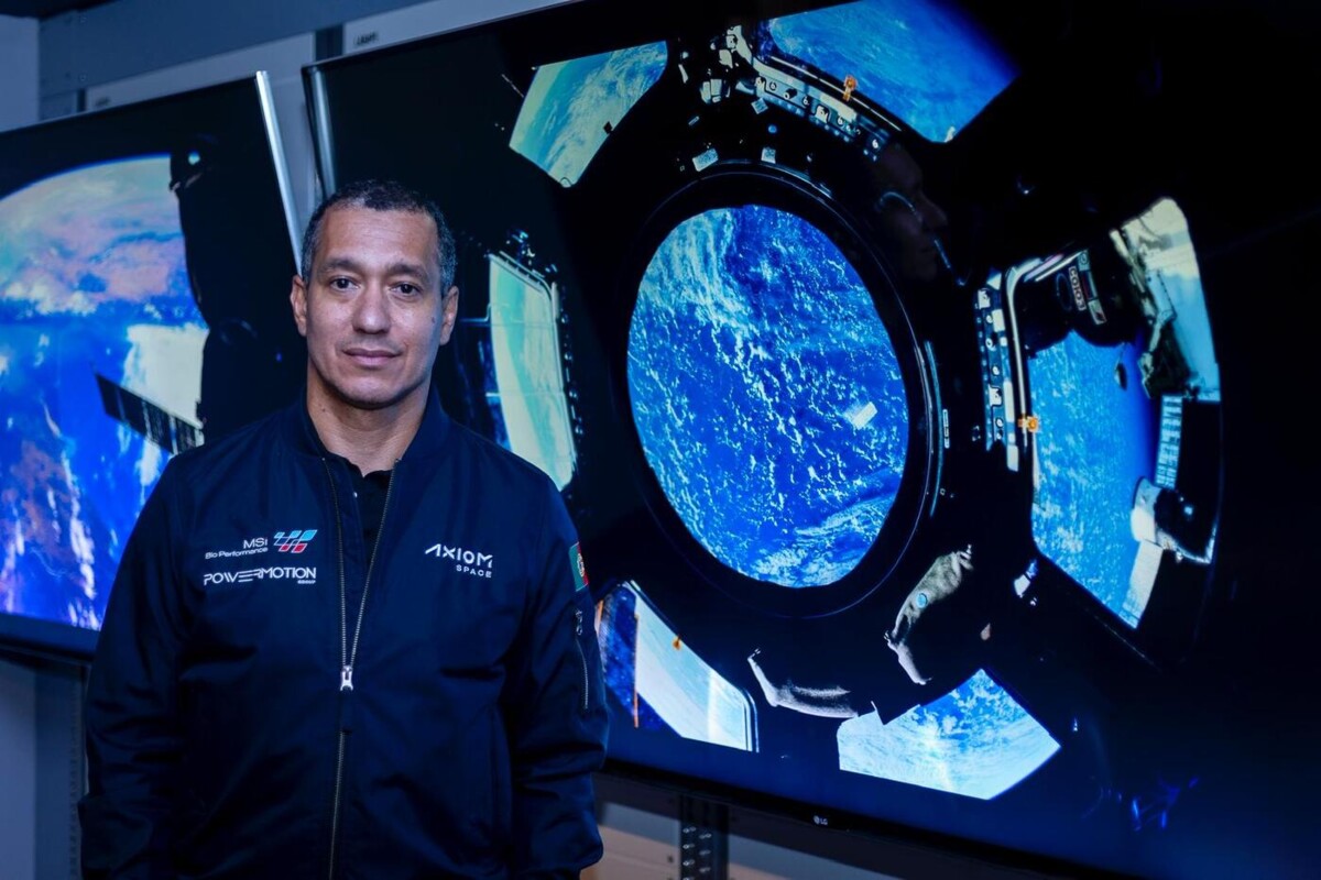 Fotografia de Emiliano Ventura à frente de dois ecrãs onde estão imagens espaciais