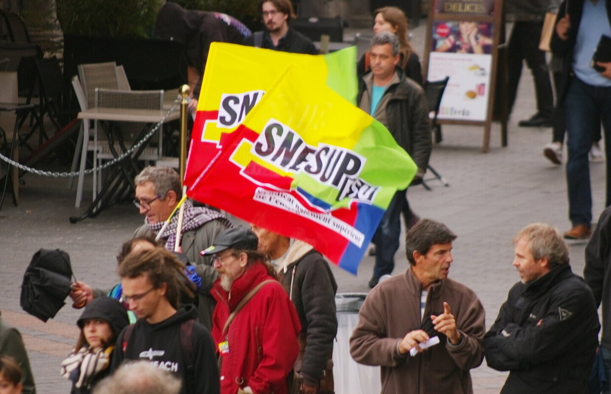 Imagem de uma manifestação, com cerca de dez pessoas, em que estão duas bandeiras do sindicato do Ensino Superior.