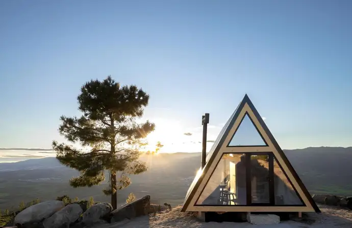 Uma casa triangular construída no topo da montanha ao nascer do sol