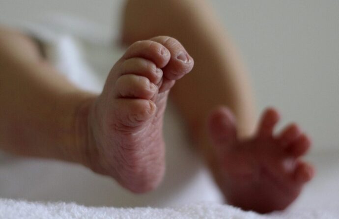 Pés de bebé, vistos de baixo, focado no pé direito da criança.