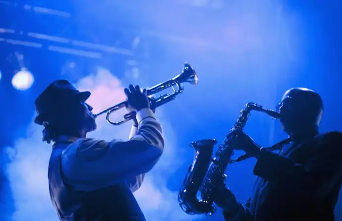 Duas pessoas num concerto de jazz, uma a tocar trompete e outra saxófone.