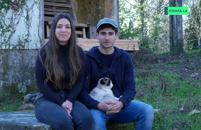 Casal de jovens sentado num jardim com um gato ao colo