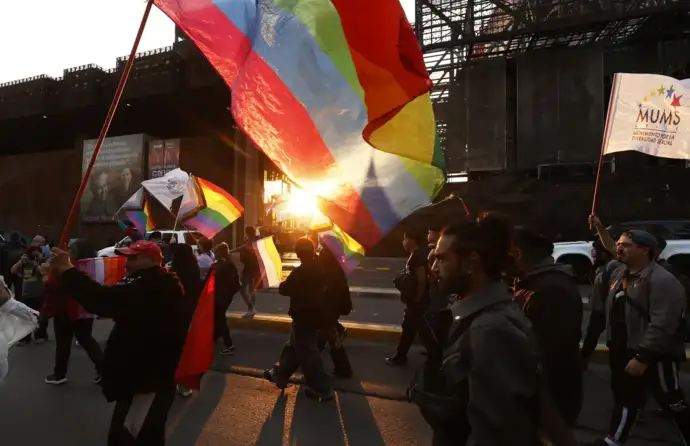 Marcha pelos direitos LGBTQI+, com bandeiras ao pôr-do-sol, em Santiago, Suiça.