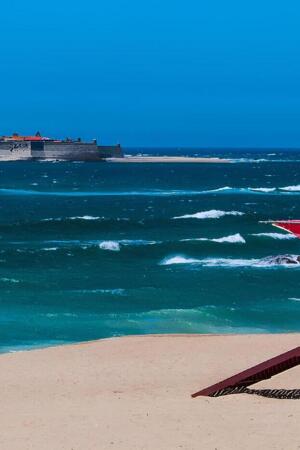 Costa da praia de Moledo, em Caminha, com um posto de salvamento e um navio no fundo.
