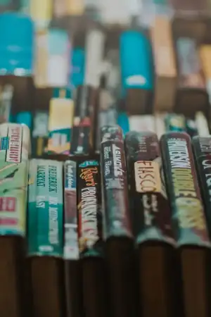 Uma série de livros, uns ao lado dos outros, onde se vê várias lombadas de livros.