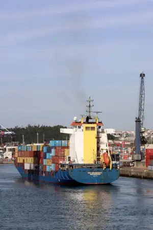 Porto de Leixões, com um barco com contentores a passar no meio de uma ponte móvel.