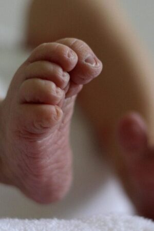 Pés de bebé, vistos de baixo, focado no pé direito da criança.