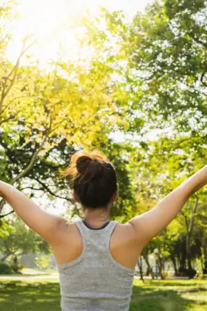 Imagem de uma senhora no meio de um parque verde a fazer exercício físico