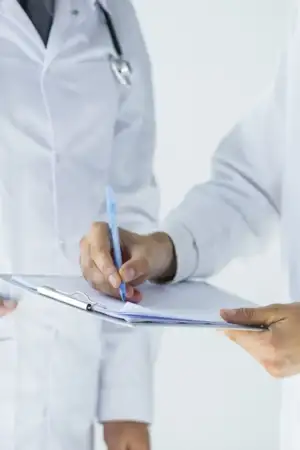 Dois médicos, vestidos de bata branca a analisar uns documentos