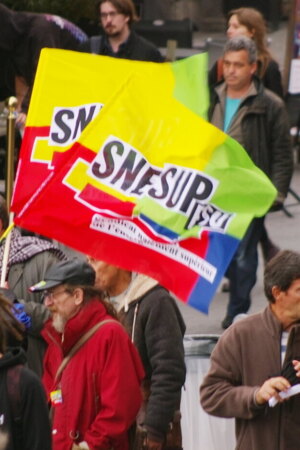 Imagem de uma manifestação, com cerca de dez pessoas, em que estão duas bandeiras do sindicato do Ensino Superior.