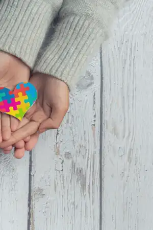 Mãos a segurar coração com símbolo de autismo