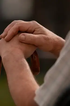 Mão de um senhor mais velho apoiado numa bengala