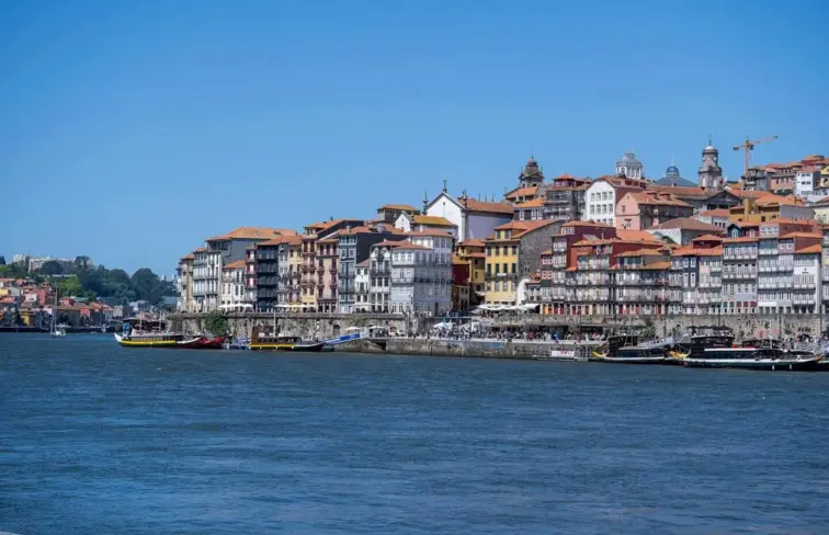 A Ribeira, no Porto, com o rio Douro e vários edifícios e barcos.