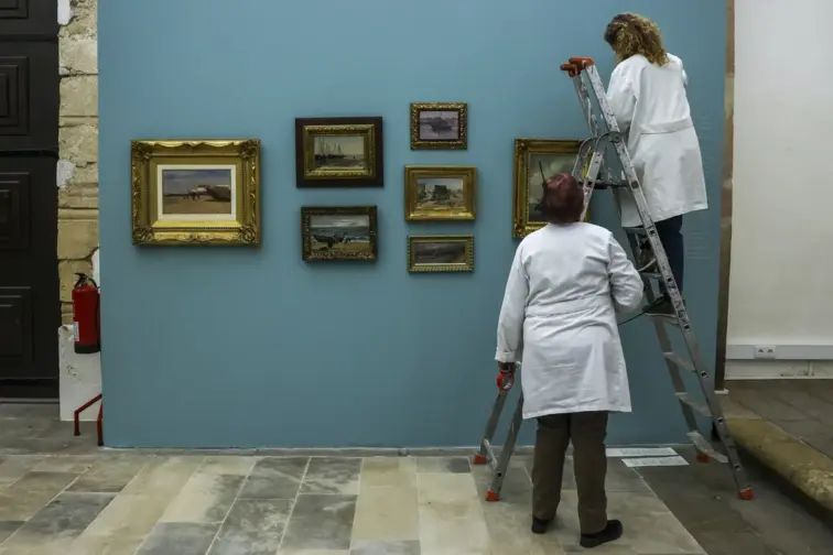 Duas pessoas a colocarem os quadros em exposição