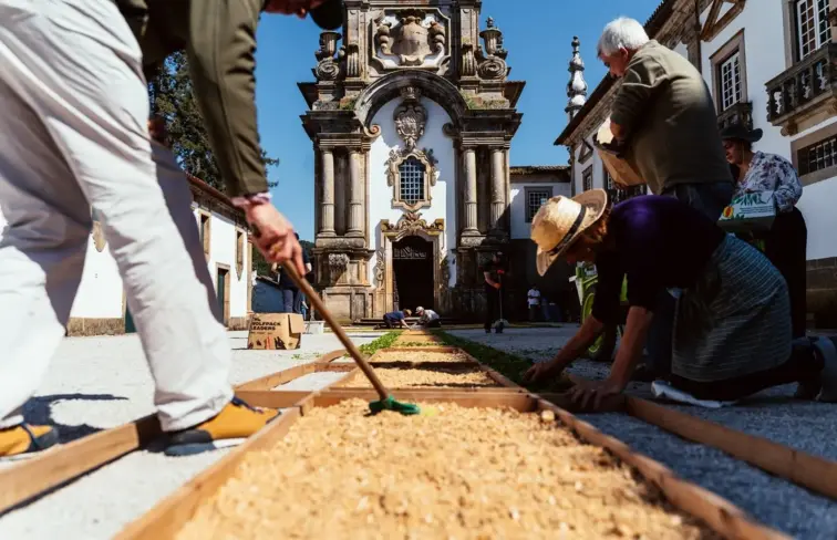 Pessoas a fazerme o tapete de flores na rua.