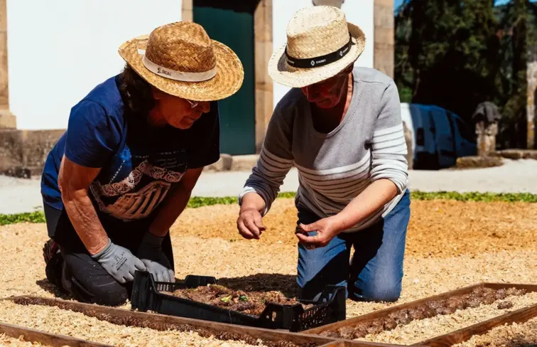 Duas mulheres colocam flores no molde no chão.