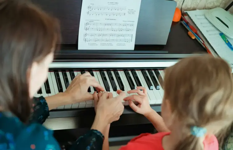 Aula de piano entre aluna e professora
