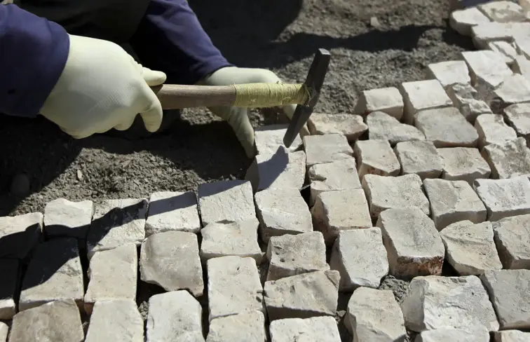 Calceteiro a colocar pedras na calçada portuguesa