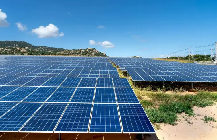 Um campo repleto de painéis solares, num dia assolarado.