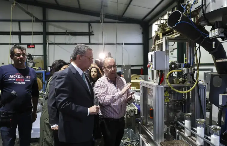 Seguro dentro de uma fábrica de velas, junto a uma máquina, com dono da empresa.