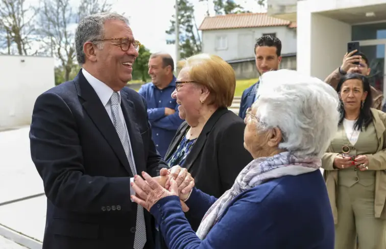 Seguro dá a mão a idosa e sorri enquanto falam.
