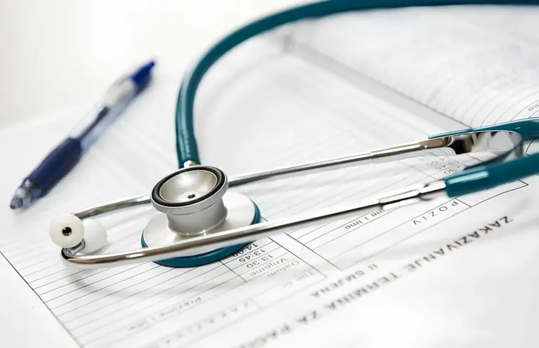 Um estetoscópio em cima de um caderno e uma caneta.