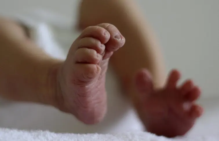 Pés de bebé, vistos de baixo, focado no pé direito da criança.
