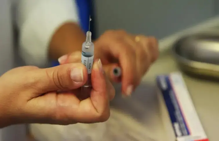 Mão direita de uma senhora a segurar uma vacina