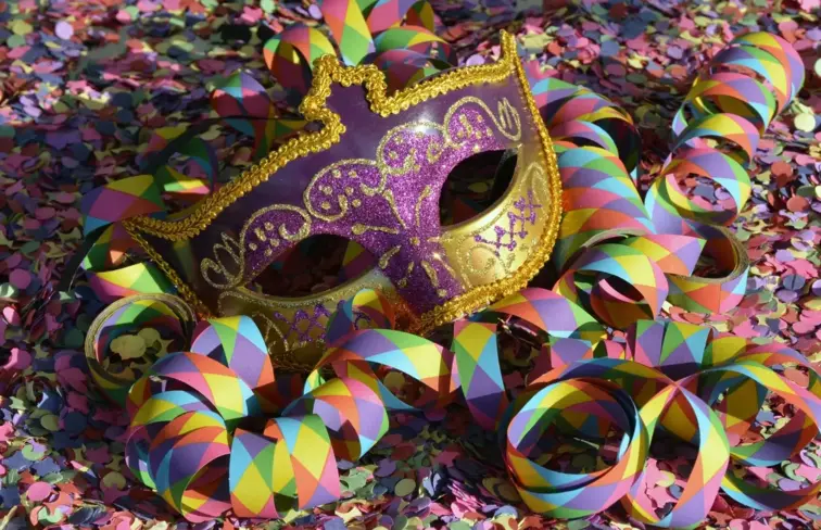 Uma máscara de Carnaval no meio de confetis e serpentinas.