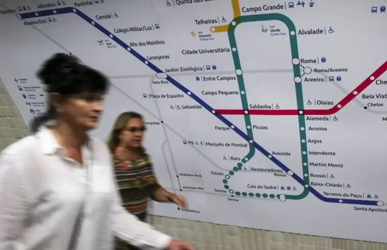Duas senhoras a caminhar diante de um mapa da rede da metro de Lisboa
