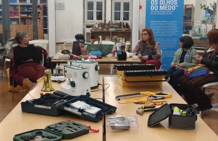 mulheres estão sentadas ao redor de uma mesa com ferramentas para obras e reparações