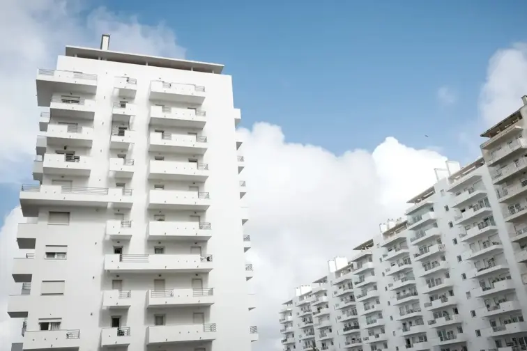 Edifícios residenciais de fachada branca e com muitos andares.