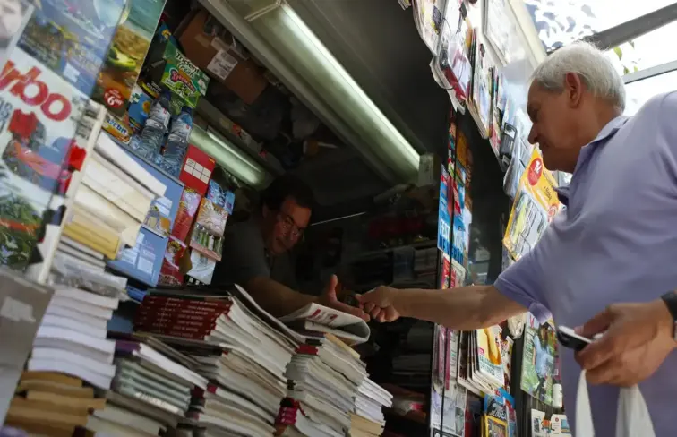 Homem a interagir com funcionário de quiosque de rua.