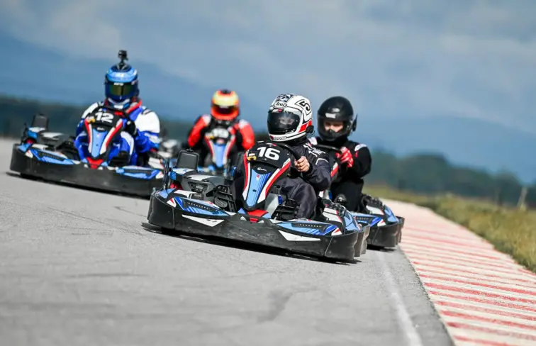 quatro pilotos de kart correm numa pista