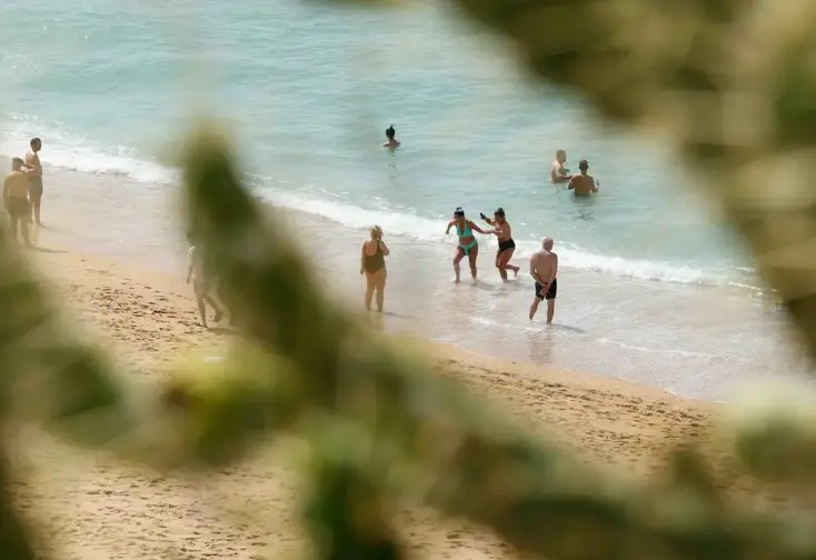 Pessoas a irem a banhos numa praia.