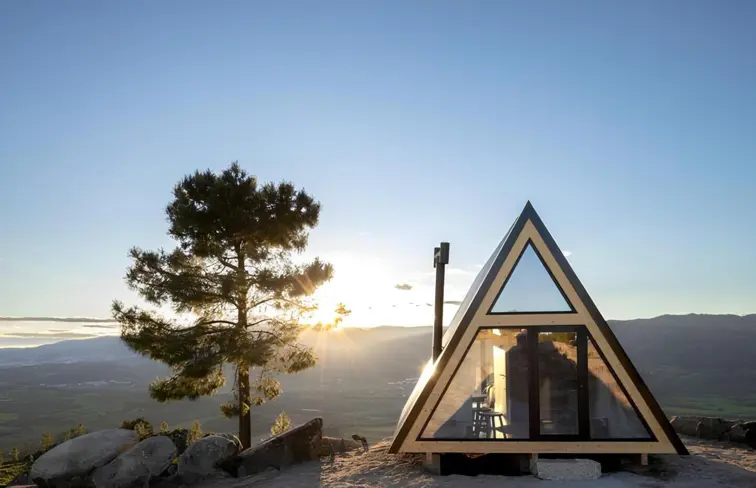 Uma casa triangular construída no topo da montanha ao nascer do sol