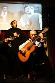 Fadista num palco, com dois guitarristas à frente, em Coimbra.