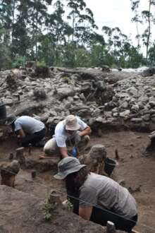 Sítio arqueológico com arqueólogos em trabalho