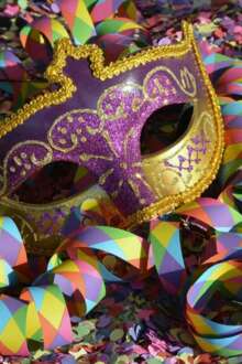 Uma máscara de Carnaval no meio de confetis e serpentinas.