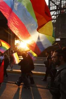 Marcha pelos direitos LGBTQI+, com bandeiras ao pôr-do-sol, em Santiago, Suiça.