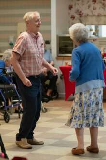 Dois idosos em pé durante atividade social