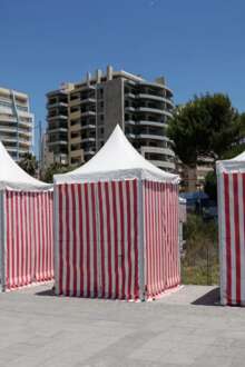 Barracas de praia listradas com edifícios atrás,