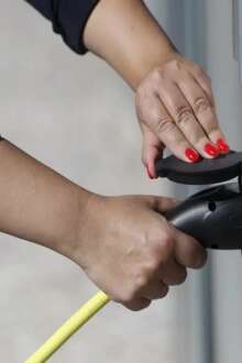 Mãos de uma pessoa a colocar viatura elétrica a carregar.