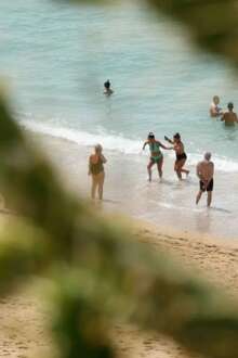 Pessoas a irem a banhos numa praia.