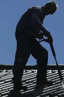 Homem a lavar telhado com pressão de água